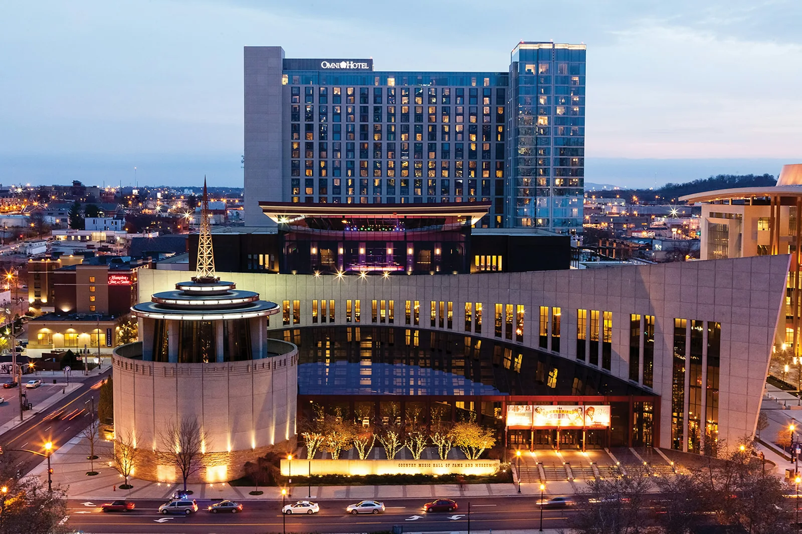 Blue-hour exterior of the Country Music Hall of Fame and Museum with the Omni Nashville Hotel visible.