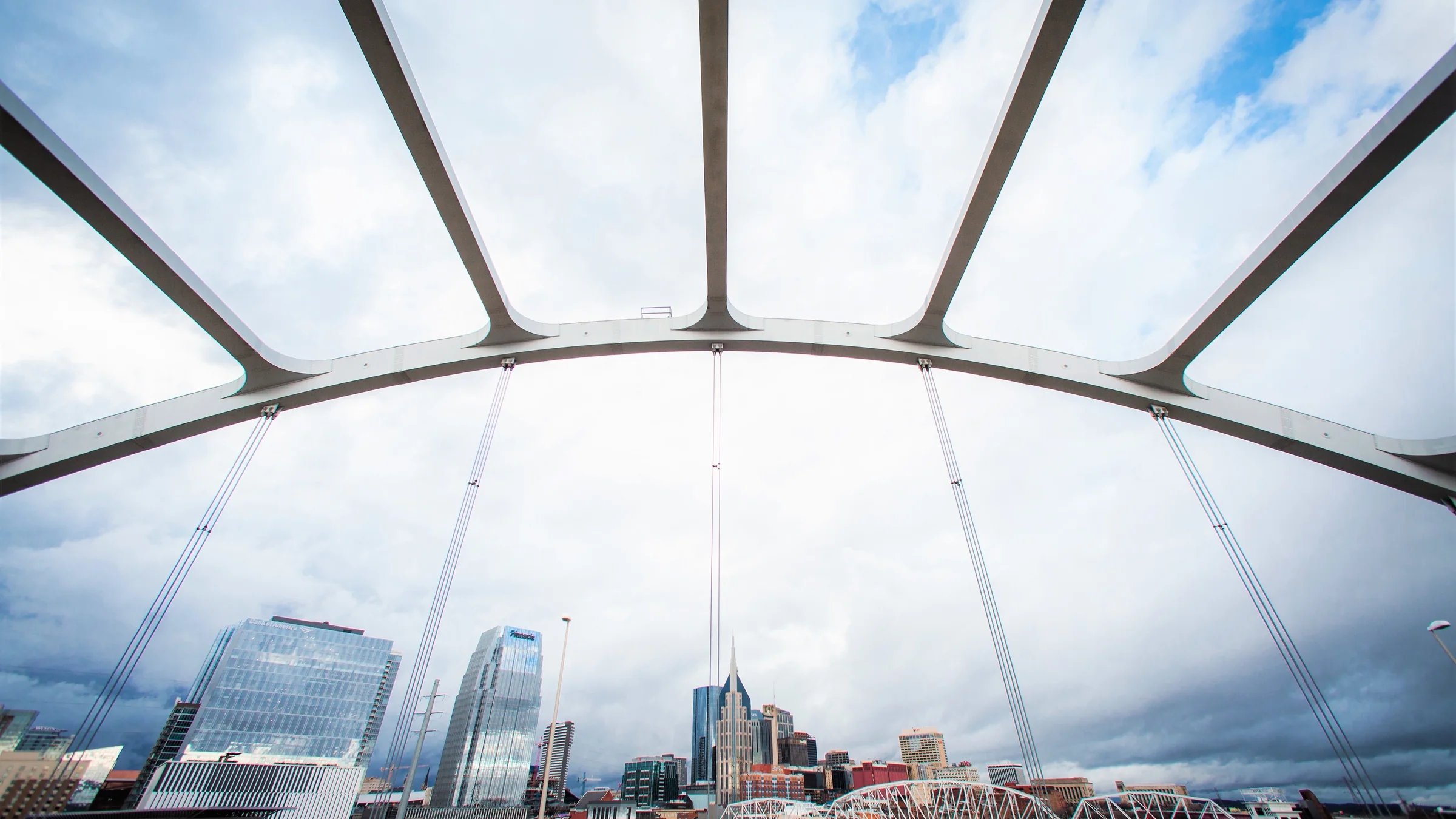 John Seigenthaler Pedestrian Bridge at blue hour with downtown skyline and Cumberland River reflections.