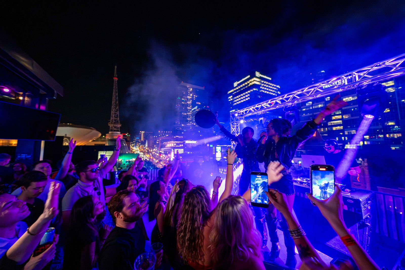 A lively rooftop party in downtown Nashville at night.