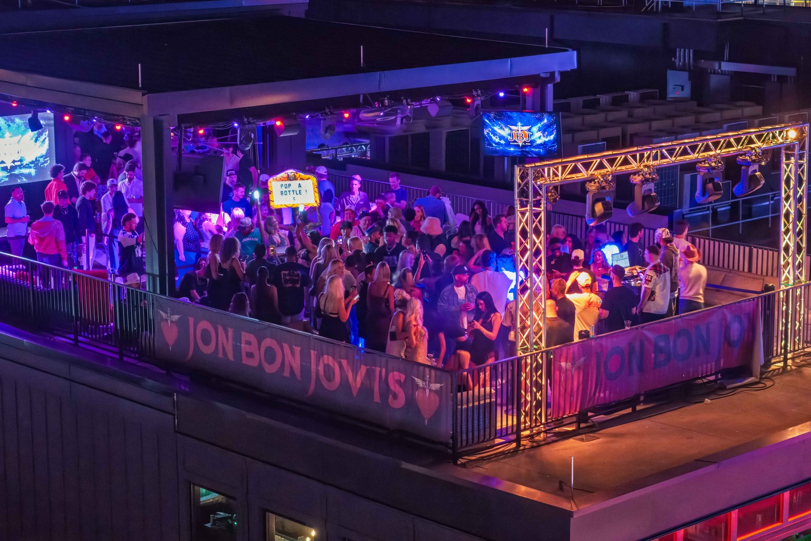 A nighttime rooftop crowd overlooking downtown Nashville.