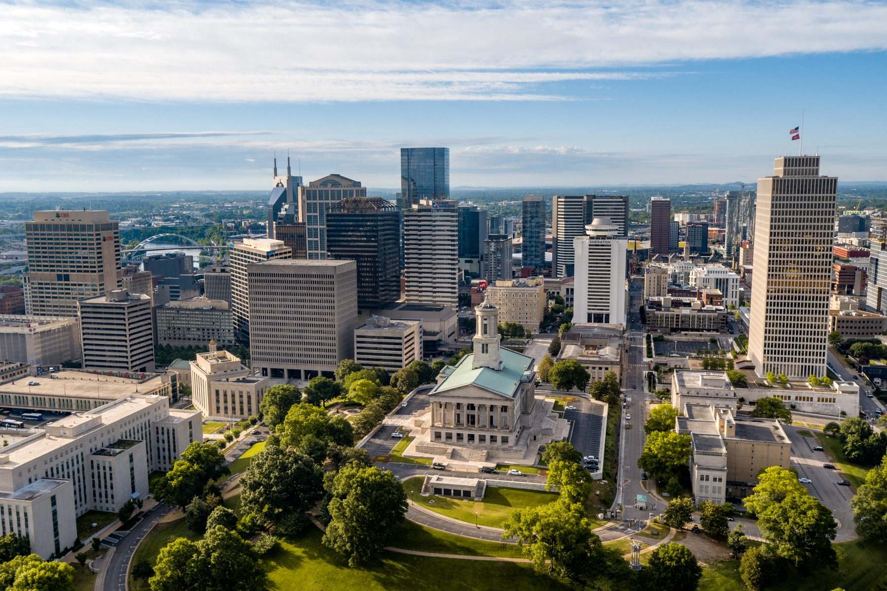 Aerial view of the Tennessee State Capitol and downtown Nashville skyline with green parkland.